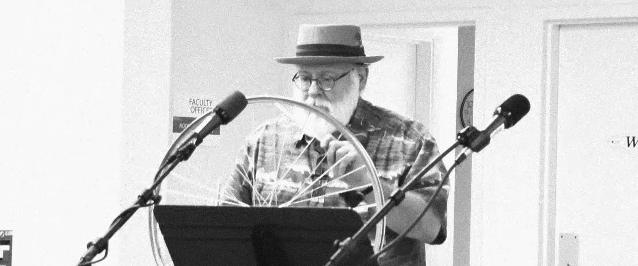 Black and white image of Mike Sanders standing in front of a microphone