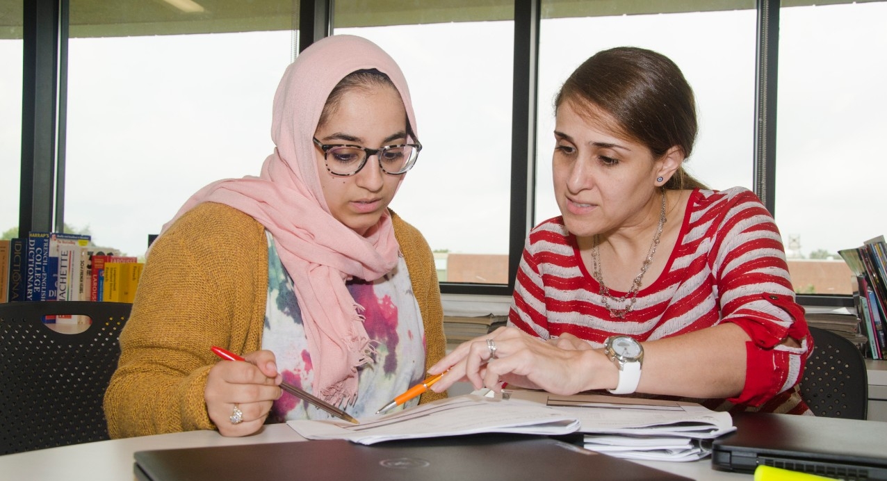 Student collaborating with professor in classroom