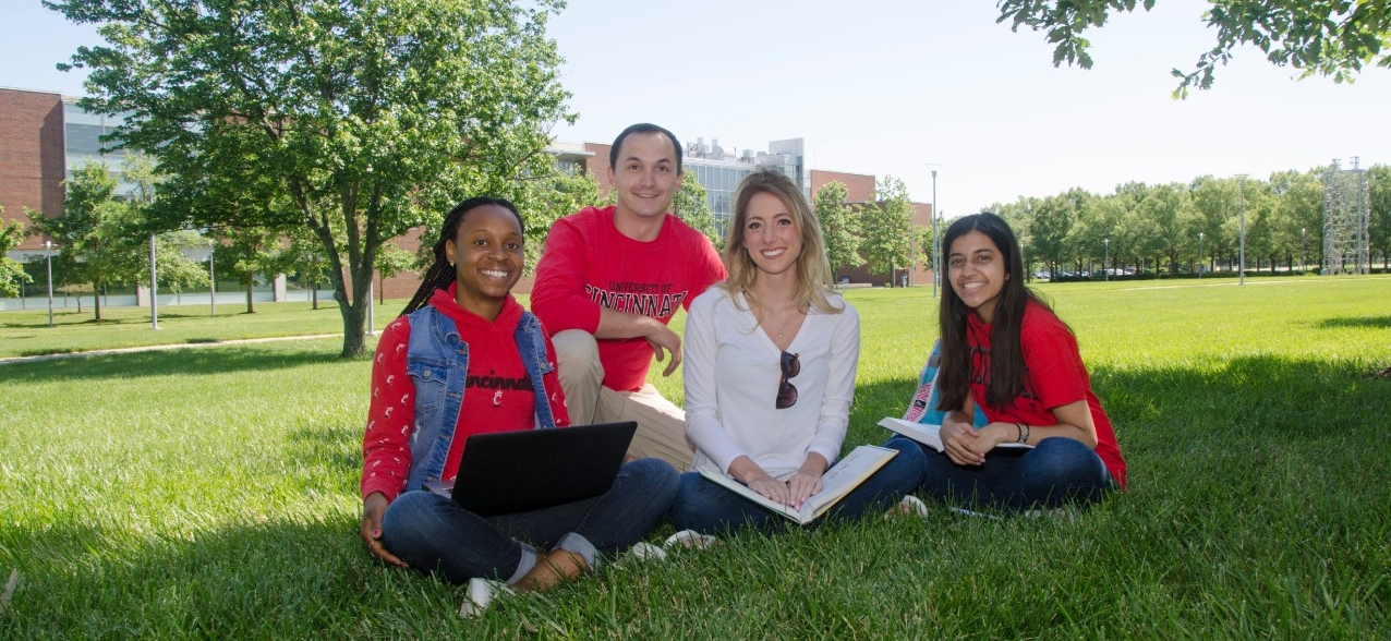 Group of students sitting in grass at UC Blue Ash College