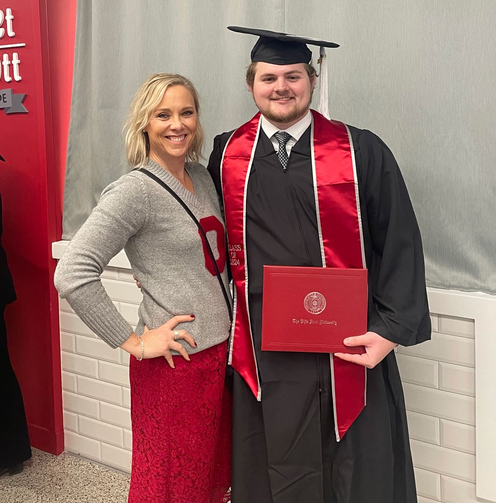 woman posing with nephew in cap and gown with diploma