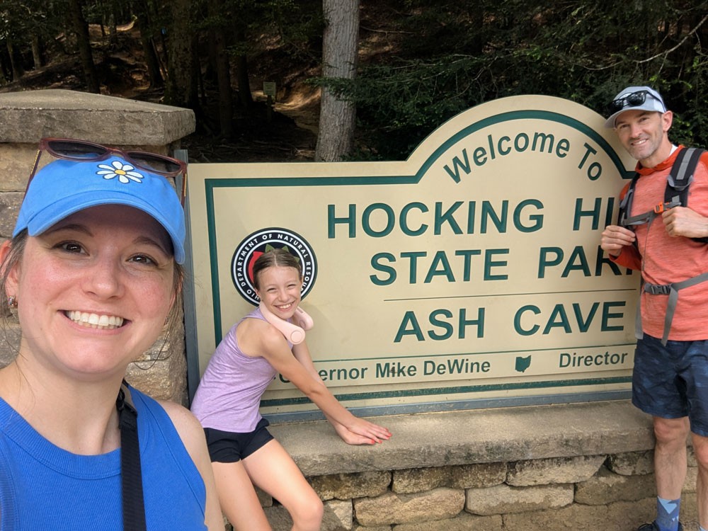 family of three posing with Hocking Hills state park sign
