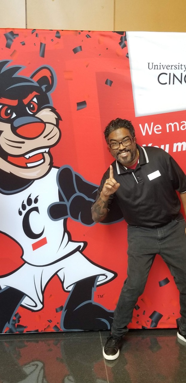 Ranjov posing with bearcat mascot poster